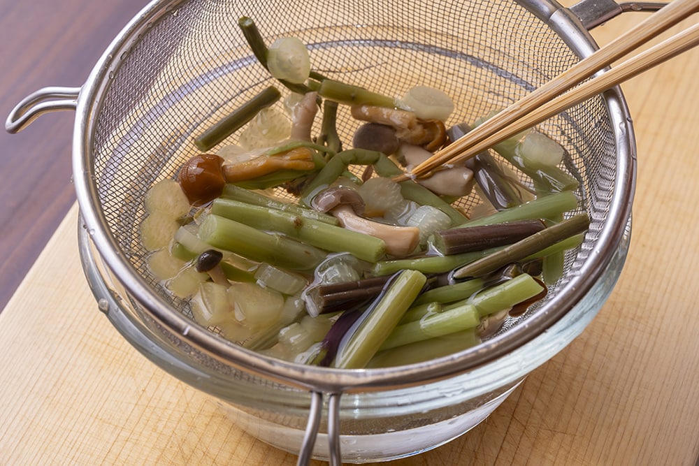 山菜をザルに入れ、サッと洗って水気をきる。