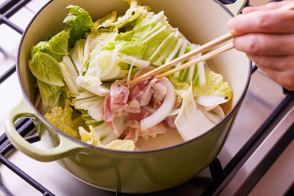 鍋に太白のごま油、にんにく、鶏肉を入れて中火にかけてサッと炒める。鶏肉が白くなってきたら、白菜と玉ねぎを入れて炒める。