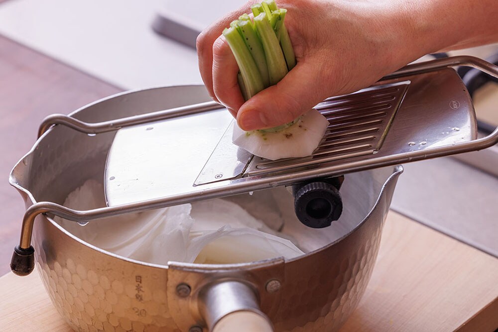 カブは皮を剥いて、スライサーで薄切りにして鍋に入れる。